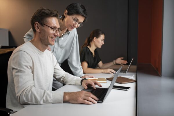 Team of professionals collaborating on laptops in a modern office environment during a Salesforce developer course training session