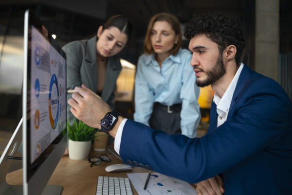 Group of professionals working on laptops in a modern office setup, collaborating on a Salesforce developer training course for career advancement