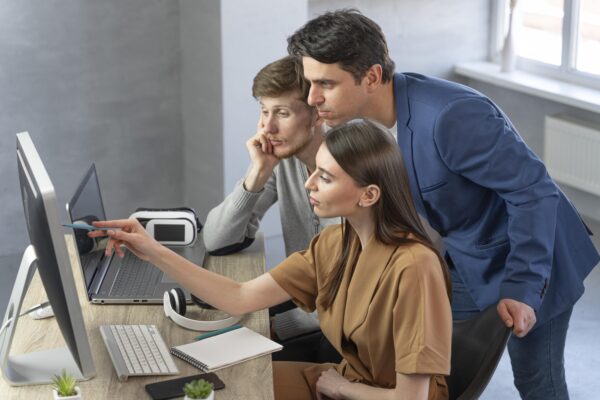 Team of professionals collaborating during a Salesforce training session, discussing data on a desktop screen in a modern office environment, Salesforce Training Program