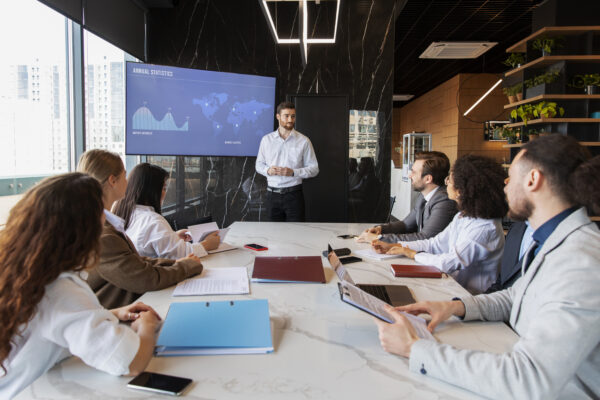 Business team attending a presentation on Salesforce AI Certification in New Jersey, discussing annual statistics and certification benefits in a modern conference room.
