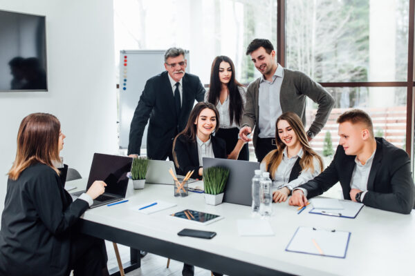Staff meeting. Group of young modern people in smart casual wear discussing something while working in the creative office . Business time. Salesforce Developer Training in Illinois