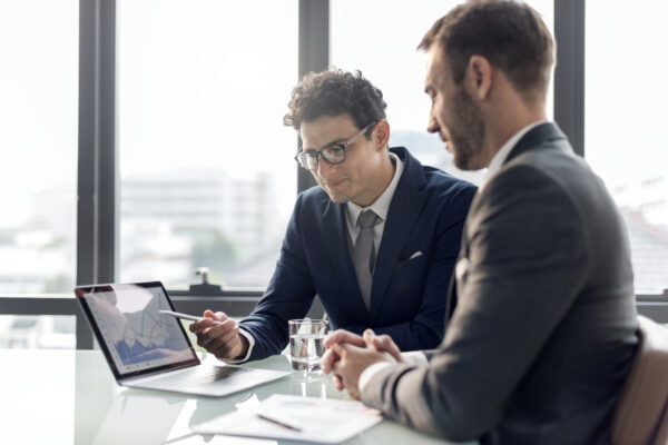 Two business professionals discussing CRM analytics on a laptop in an office setting, highlighting the benefits of using Salesforce Starter in Pennsylvania.